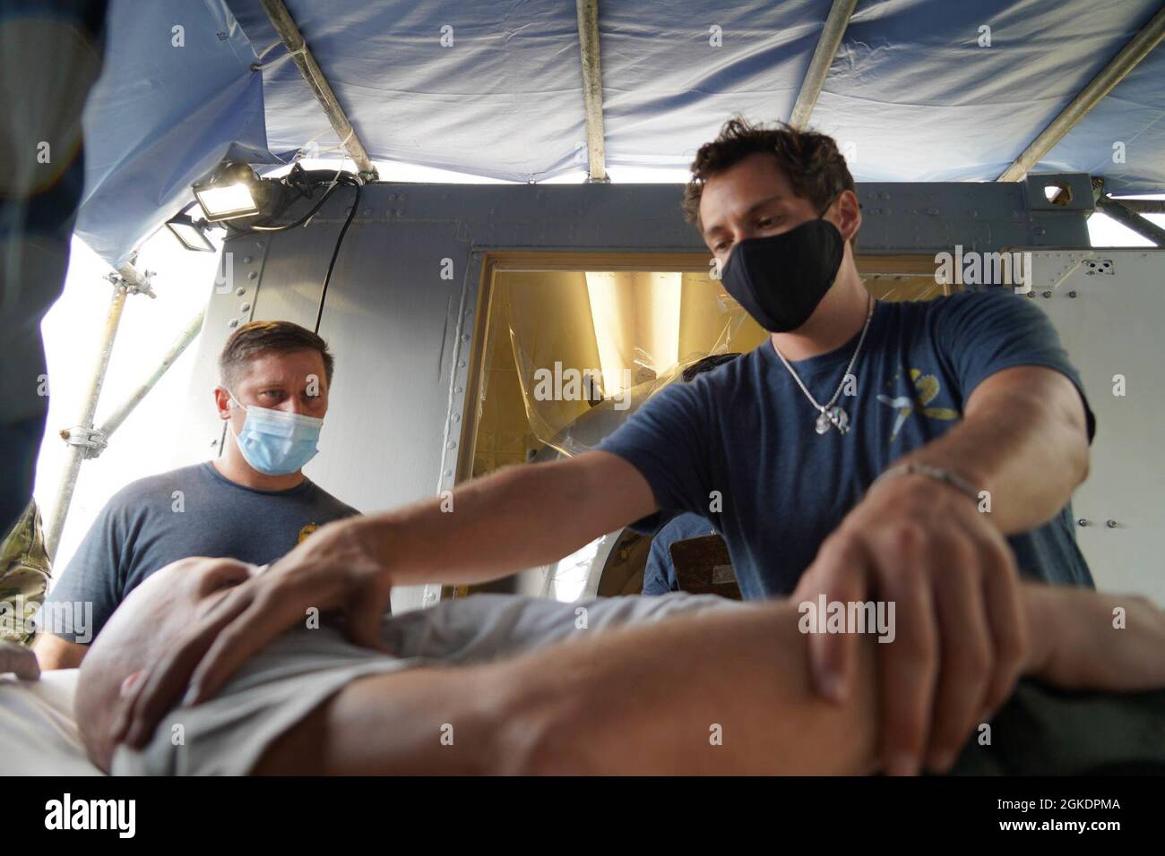 Chris Emanus, 2. Klasse des Navy-Tauers, verwaltet simulierte Hilfe für LT. Col. Matthew Hoyt, Leiter der Luft- und Raumfahrtmedizin der 15. Medizinischen Gruppe, vor der Behandlung in der hyperbaren Rekompression-Kammer während einer Übung auf der Joint Base Pearl Harbor-Hickam, Hawaii, 23. März 2021. Flugbegleiter, Matrosen und Mitglieder der JBPHH Federal Fire Department reagierten auf einen simulierten Notfall während des Fluges und begleiteten ein Mitglied der Luftbesatzung zur Behandlung in die hyperbare Kompressionskammer. Falls ein Mitglied der Luftbesatzung eine Dekompressionskrankheit erfährt, erlaubt die hyperbare Rekompressionskammer den Mitgliedern, rein o zu atmen Stockfoto