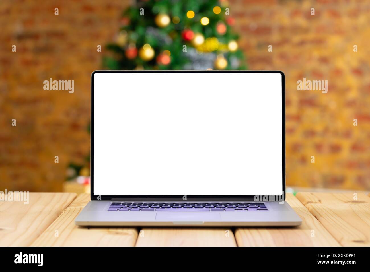 Komposition von Laptop mit Kopierplatz auf Holztisch mit weihnachtsbaum im Hintergrund Stockfoto