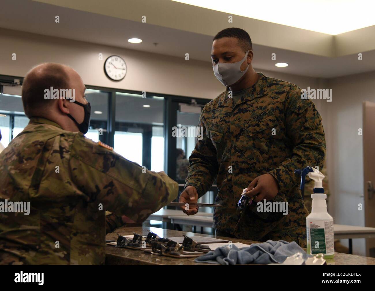 Ein Armeesoldat, der bei der COVID-19-Impftests der Nationalgarde von Michigan im Auftrag der Task Force Spartan (links) dient, überprüft während einer Impfklinik COVID-19 am Hauptquartier der Vereinten Kräfte in Lansing, Michigan, am 24. März 2021 in einer Marine. Die Klinik lieferte Impfstoffe an etwa 250 Mitarbeiter des Verteidigungsministeriums und andere Empfänger, die Tricare-Patienten in Anspruch nehmen können. Stockfoto
