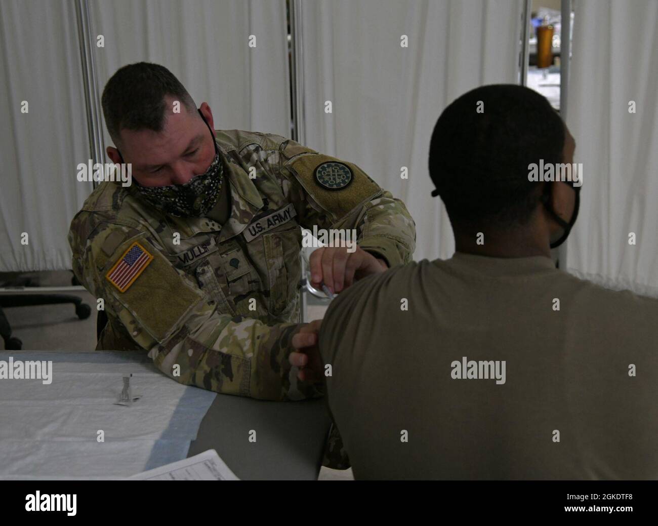 SPC der US-Armee. Lonnie Muller, Kampfmediziner, der bei der Task Force Spartan, Michigan National Guard, des COVID-19-Impfteams tätig ist, impft während einer Impfklinik COVID-19 am Hauptquartier der Vereinten Kräfte in Lansing, Michigan, am 24. März 2021 einen aktiven Soldaten. Die Klinik lieferte Impfstoffe an etwa 250 Mitarbeiter des Verteidigungsministeriums und andere Empfänger von Tricare. Stockfoto