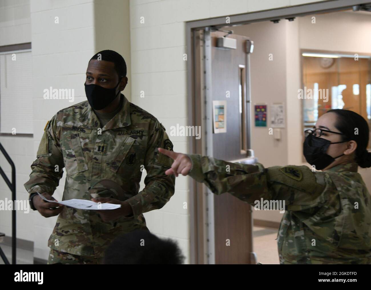 Ein Armeesoldat, der bei der COVID-19-Impftest-Task Force Spartan (rechts) der Nationalgarde von Michigan dient, weist einen aktiven Soldaten während einer COVID-19-Impfklinik am Hauptquartier der Vereinten Kräfte in Lansing, Michigan, am 24. März 2021 auf den Wartebereich. Die Klinik lieferte Impfstoffe an etwa 250 Mitarbeiter des Verteidigungsministeriums und andere Empfänger, die Tricare-Patienten in Anspruch nehmen können. Stockfoto
