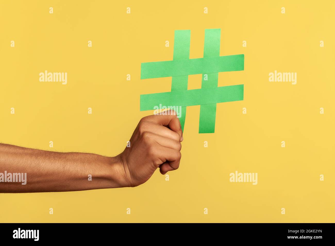 Social-Media-Konzept. Nahaufnahme von menschlicher Hand, die große grüne Hashtag-Schilder zeigt, Copyspace. Innenaufnahme des Studios isoliert auf gelbem Hintergrund Stockfoto