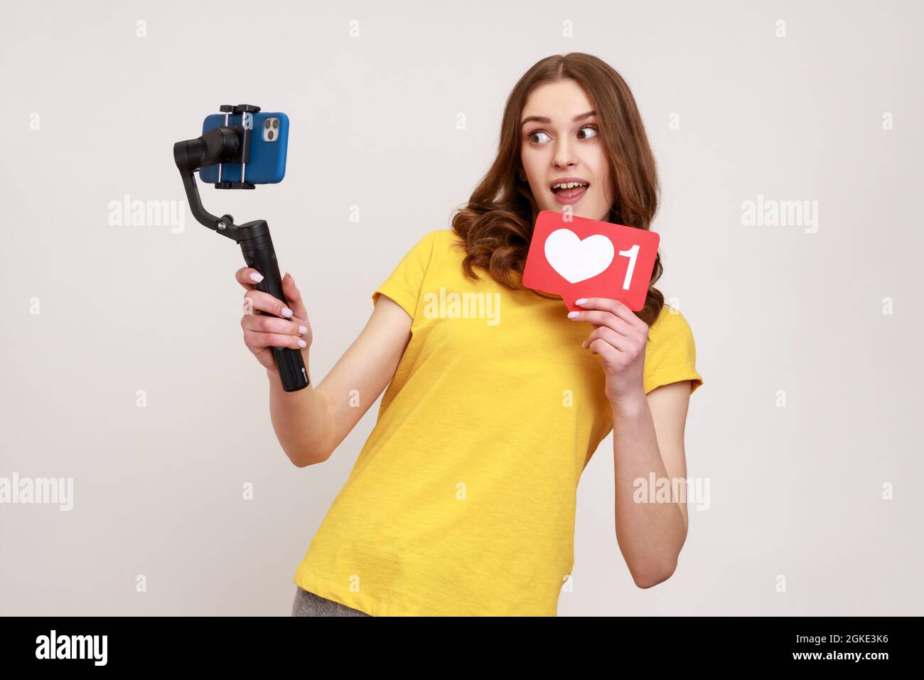 Glücklich aufgeregt Teenager blogger Mädchen sendet Livesream, mit Standycam, zeigen, um Kamera wie Symbol, Kommunikation mit Anhängern. Studio im Innenbereich Stockfoto