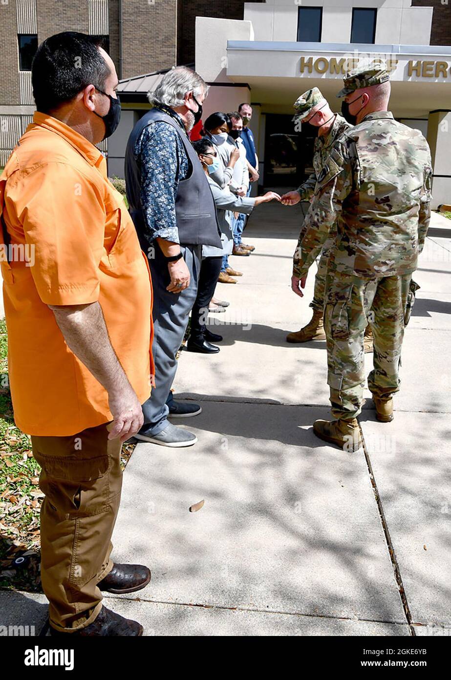 Der stellvertretende Kommandant von IMCOM, Major General Timothy P. McGuire, verleiht IMCOM-Münzen an Zivilarbeiter während eines Besuchs im Joint Readiness Training Center und Fort Polk am 23. März, als Oberst Ryan K. Roseberry, Garnisonskommandant von Fort Polk, auf sie schaut. Stockfoto