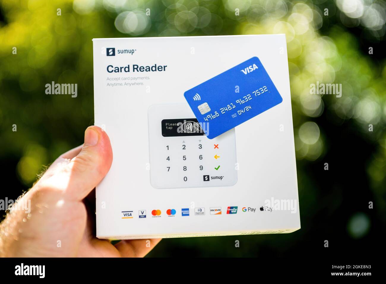 Männliche Hand hält neuen vorderen Teil des Pakets mit SumUp EMV-Kartenleser, der Magnetstreifen lesen kann Stockfoto