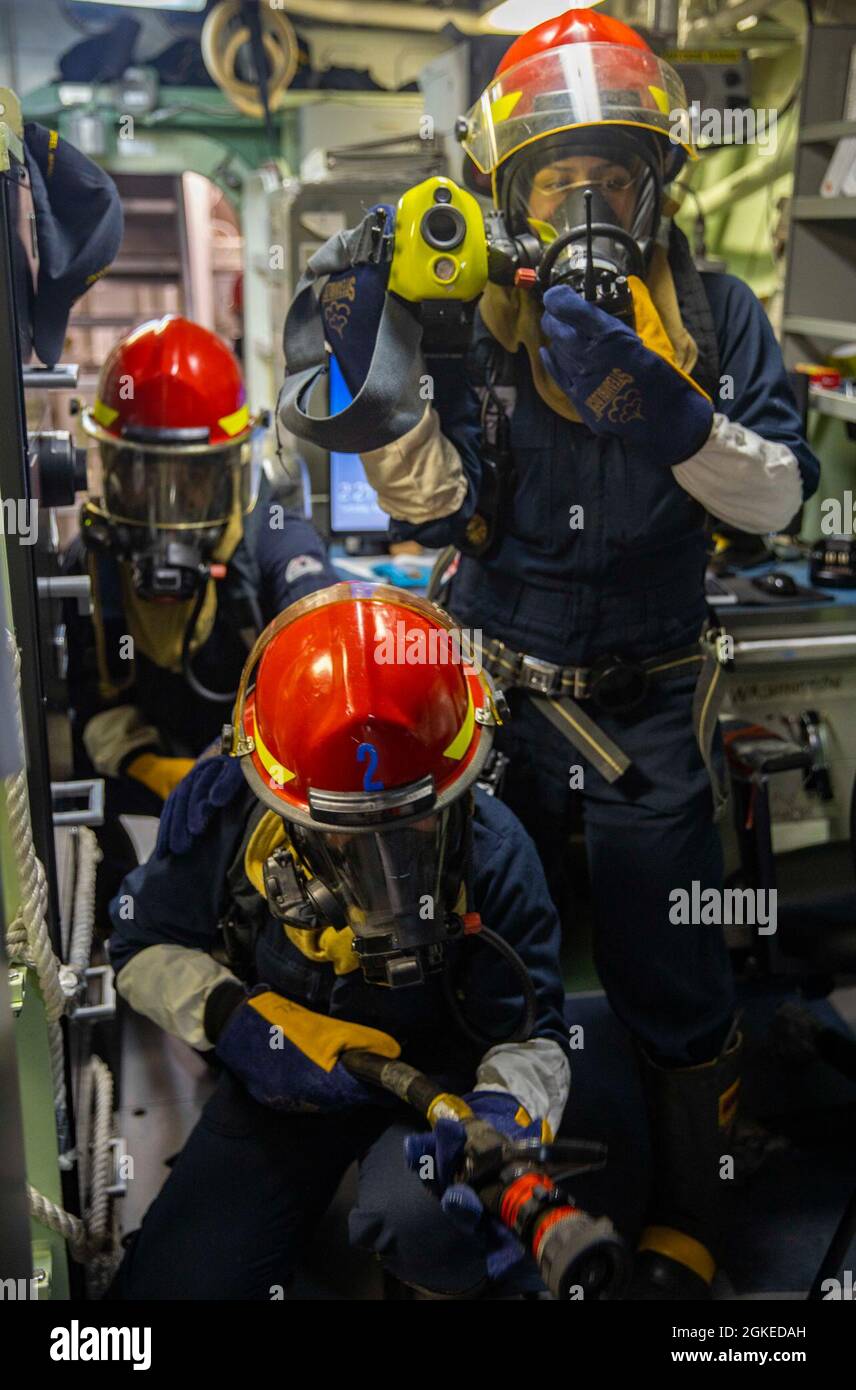 OSTCHINESISCHES MEER (30. März 2021) Matrosen, die dem Lenkraketen-Zerstörer USS Curtis Wilbur (DDG 54) der Arleigh Burke-Klasse einen Schlauch während der Schadenskontrollübungen zugewiesen wurden. Curtis Wilbur wird der Task Force 71/Destroyer Squadron (DESRON) 15 zugewiesen, der größten Vorwärtsdresse der Marine und der wichtigsten Oberflächenkraft der US-Flotte der 7. Flotte Stockfoto