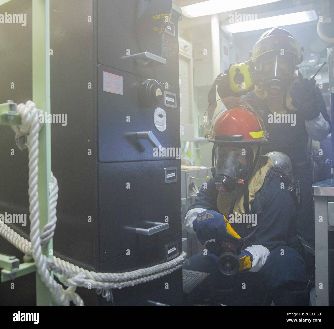 OSTCHINESISCHES MEER (30. März 2021) Matrosen, die dem Lenkraketen-Zerstörer USS Curtis Wilbur (DDG 54) der Arleigh Burke-Klasse einen Schlauch während der Schadenskontrollübungen zugewiesen wurden. Curtis Wilbur wird der Task Force 71/Destroyer Squadron (DESRON) 15 zugewiesen, der größten Vorwärtsdresse der Marine und der wichtigsten Oberflächenkraft der US-Flotte der 7. Flotte Stockfoto