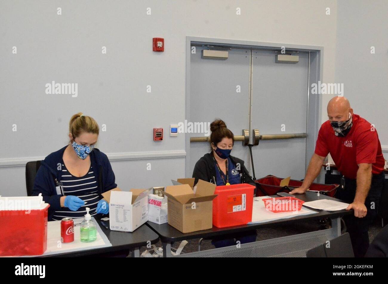 (Links) Courtney Dowling, eingetragene Krankenschwester/Krankenschwester Courtney Dowling; (Zentrum) Impfkoordinatorin für den Coastal Health District, Paige Lightsey; und Todd Wyckoff, Director of Emergency Preparedness im Coastal Health District, bereiten erste Impffläschchen für Studenten am FLETC-Glynco, März 30 vor. Stockfoto