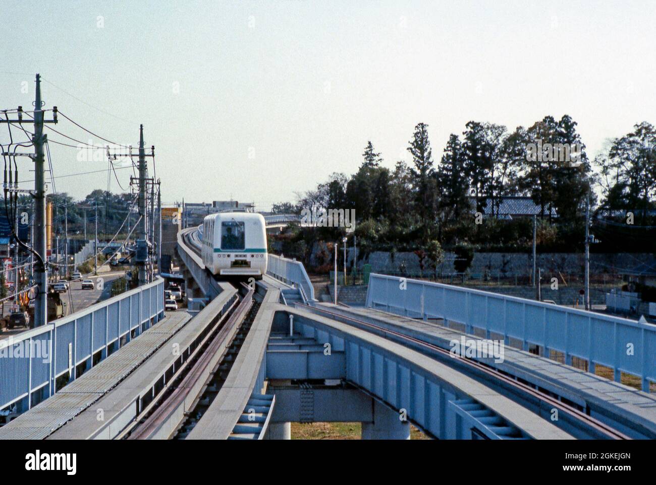 Ein Zug oder eine Person, die sich auf einem Viadukt auf der Yaman Kōen Yūkarigaoka-Linie (Yūkarigaoka Sen), Yūkarigaoka, Sakura, Chiba, in der Nähe von Tokio, Japan ca. 1983. Die lokale Linie, die von Yaman Co Ltd, dem Entwickler der neuen Stadt Yūkarigaoka, gebaut wurde, wurde zwischen 1982 und 1983 in zwei Etappen eröffnet. Es fährt in einer Schleife zum und vom Bahnhof Yūkarigaoka. Es verfügt über sechs Stationen und eine Strecke von nur 2.5 Meilen. Die Züge bestehen aus drei Wagen, die auf Gummireifen auf flachen breiten Schienen fahren. Dieses Bild stammt von der Farbtransparenz eines Amateurfotografen – einem Vintage-Foto aus den 1980er Jahren. Stockfoto