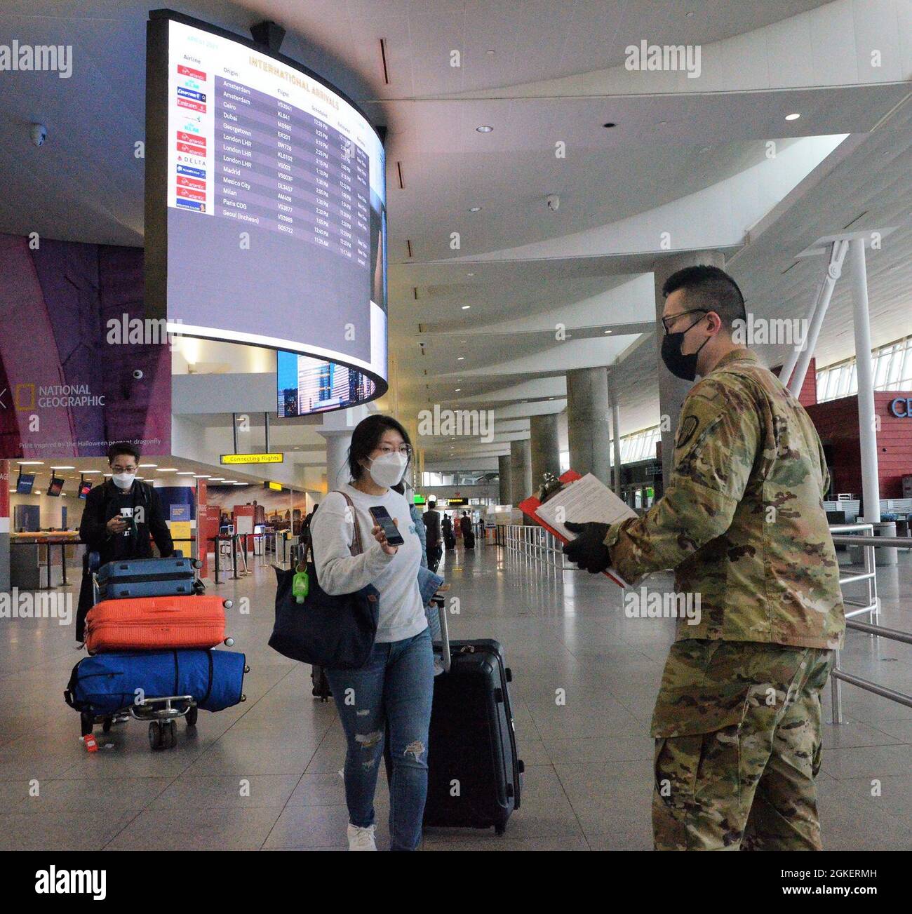 Enda Wang, eine Spezialistin der New Yorker Armee der Nationalgarde, ein Mitglied der 187. Signal Company, überprüft das Mobiltelefon eines internationalen Reisenden, der am John F Kennedy International Airport, New York ankommt, um sicherzustellen, dass sie am 1. April die digitale Version des New York State Travel Health Form ausgefüllt hat. 2021. Zwischen dem 16. Oktober und dem 1. April prüften und sammelten Mitarbeiter der New Yorker Nationalgarde über 3 Millionen elektronische und Papierformulare. ( US A Stockfoto