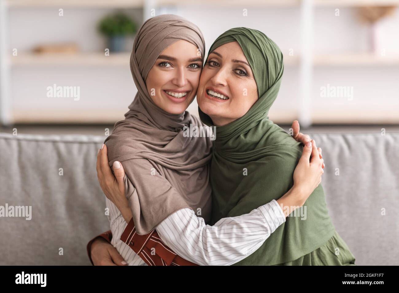 Glückliche Muslimische Mutter Und Erwachsene Tochter Umarmt Tragen Hijab Indoor Stockfoto