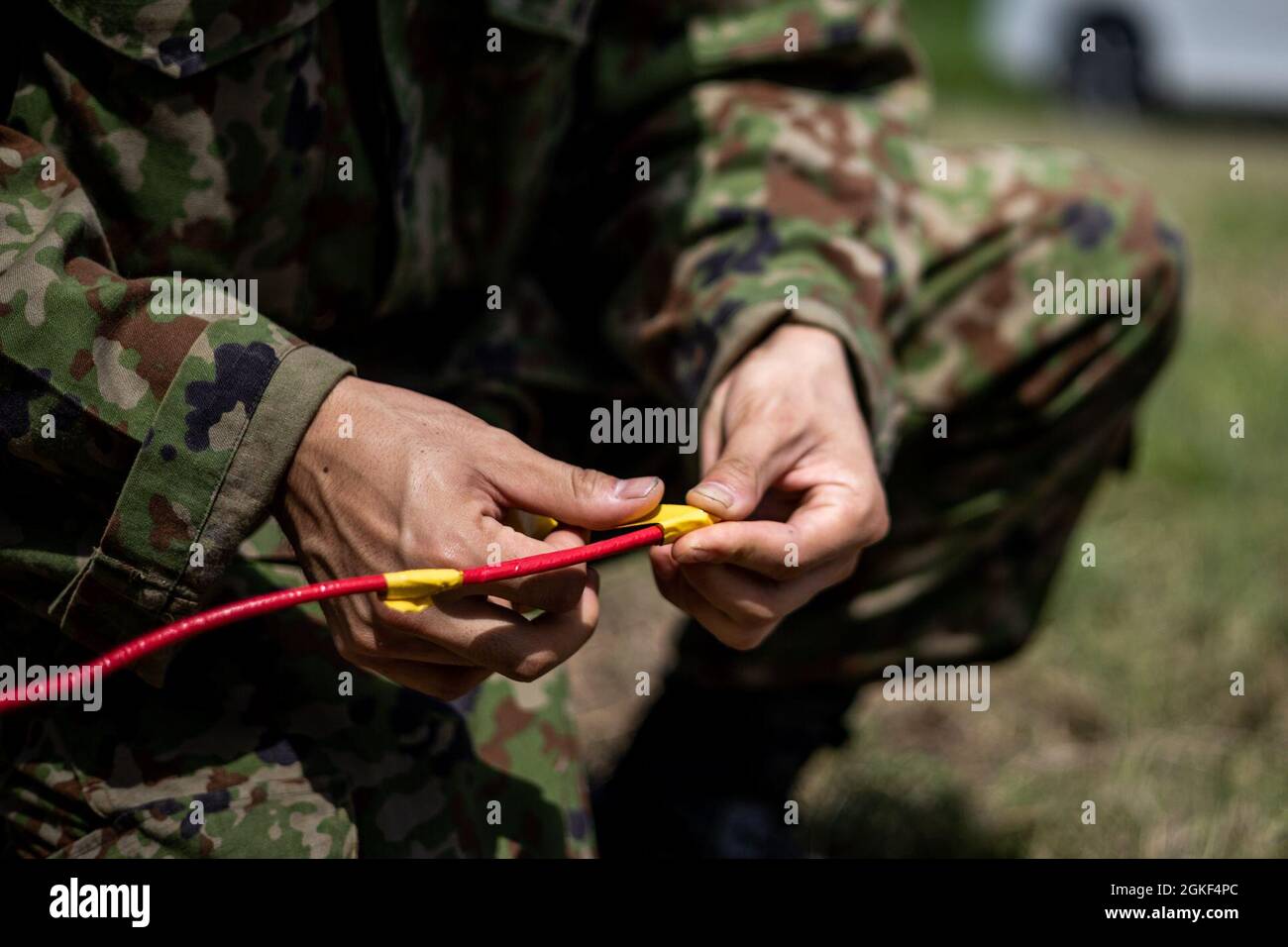 Japan Ground Self-Defense Force (JGSDF) Sgt. Takashi Kawahara, ein Sprengstoffentsorgungstechniker (EOD) mit der 101. Sprengstoffentsorgungseinheit, wird mit einem nichtelektrischen Detonator in der IE Shima Training Facility (ISTF), Okinawa, Japan, 6. April 2021 in Sprengladung gespült. In den letzten fünf Jahren wurde auf Iejima gefundene, nicht explodierte Sprengkörper in Erwartung der Zerstörung gelagert. Auf Antrag des Bürgermeisters des IE Village, JGSDF und des Marine Corps Base Butler EOD führten Techniker kombinierte Operationen durch, um diese Gefahren zu zerstören. ISTF ist die einzige aktive Abbruchkette an Bord von Iejima, wo es Stockfoto