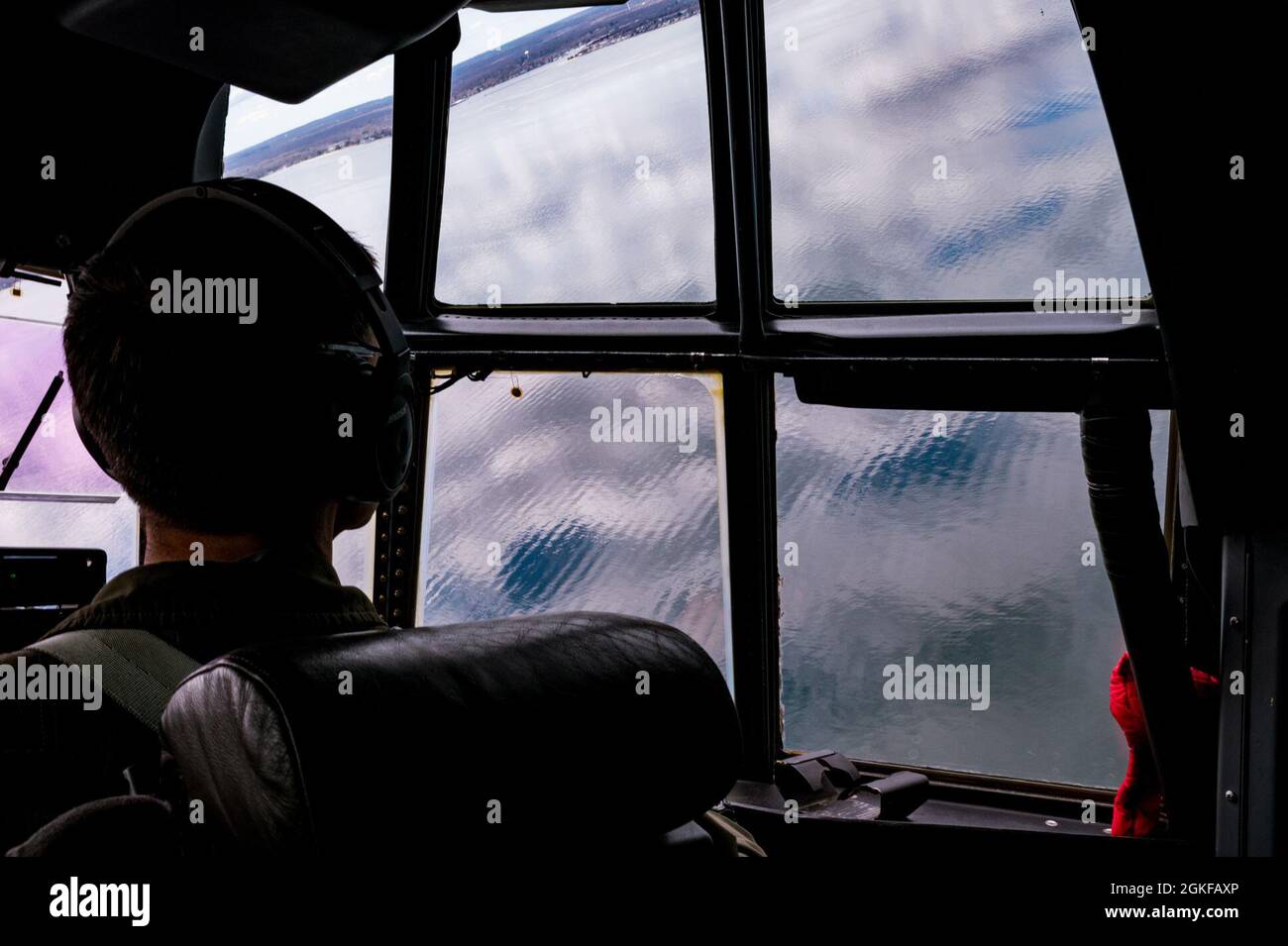 Air National Guard Maj. Ian Friel, ein Pilot des 143d Airlift Wing, betreibt einen C130J Super Hercules, 7. April 2021, über Narragansett Bay, R.I. Friel, die Luftbesatzung der 143 AW und der U.S. Special Operations Forces, haben sich zusammengetan, um hochgelegene Fallschirmsprünge mit geringer Öffnung durchzuführen. Der C130J kann auf rauen, schmutzigen Streifen betrieben werden und ist der beste Transport für Luftabtropftruppen und Ausrüstung unter verschiedenen Bedingungen, überall auf der Welt. Stockfoto