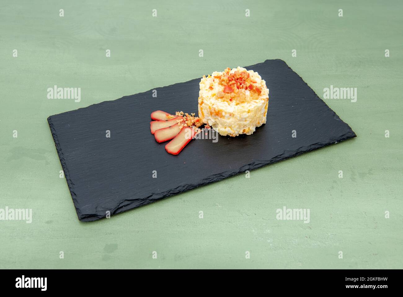 Russischer Salat mit Maruca Roe auf schwarzem Schieferteller Stockfoto