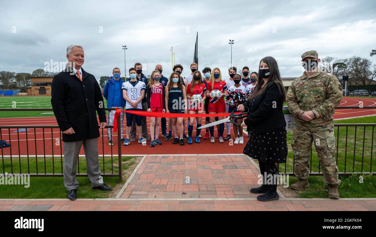 Der Oberst der US-Luftwaffe, Landon Phillips, Kommandant der 48th Mission Support Group, nimmt am 9. April 2021 an einer Zeremonie zum Schneiden von Bändern mit Mitarbeitern und Studenten des Verteidigungsministeriums in der Royal Air Force Lakenheath, England, Teil. Die Zeremonie wurde durchgeführt, um an die gemeinsamen Bemühungen von DoDEA und dem Air Force Fitness Center bei der Eröffnung der neu gebauten Laufstrecke und des neuen Feldes zu erinnern. Stockfoto