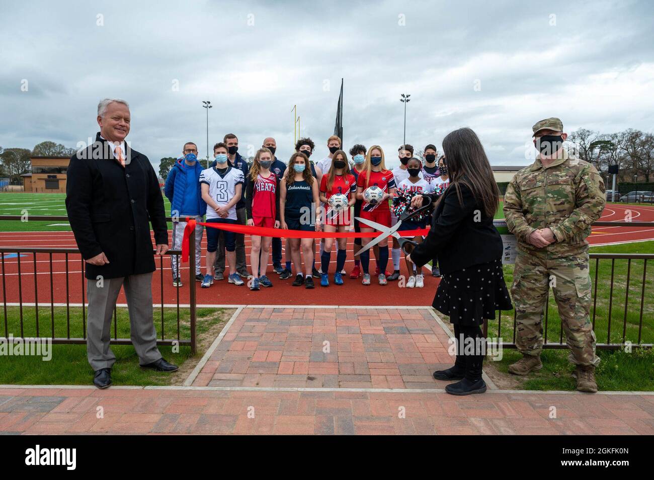 Der Oberst der US-Luftwaffe, Landon Phillips, Kommandant der 48th Mission Support Group, nimmt am 9. April 2021 an einer Zeremonie zum Schneiden von Bändern mit Mitarbeitern und Studenten des Verteidigungsministeriums in der Royal Air Force Lakenheath, England, Teil. Die Zeremonie wurde durchgeführt, um an die gemeinsamen Bemühungen von DoDEA und dem Air Force Fitness Center bei der Eröffnung der neu gebauten Laufstrecke und des neuen Feldes zu erinnern. Stockfoto