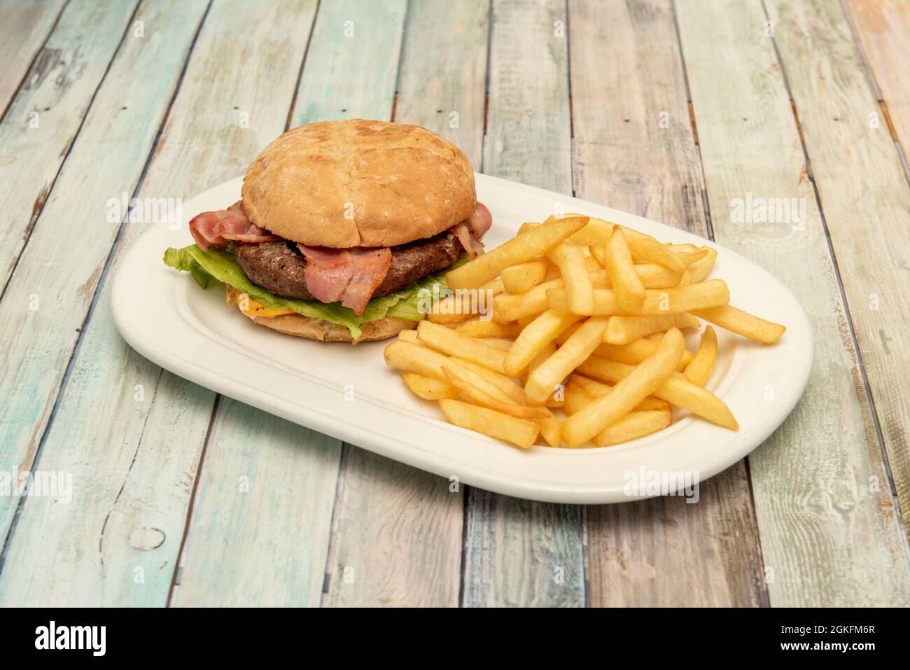 Klassischer Rindfleischburger mit Käse, Salat und Speck und Guranicion von Pommes Frites Stockfoto