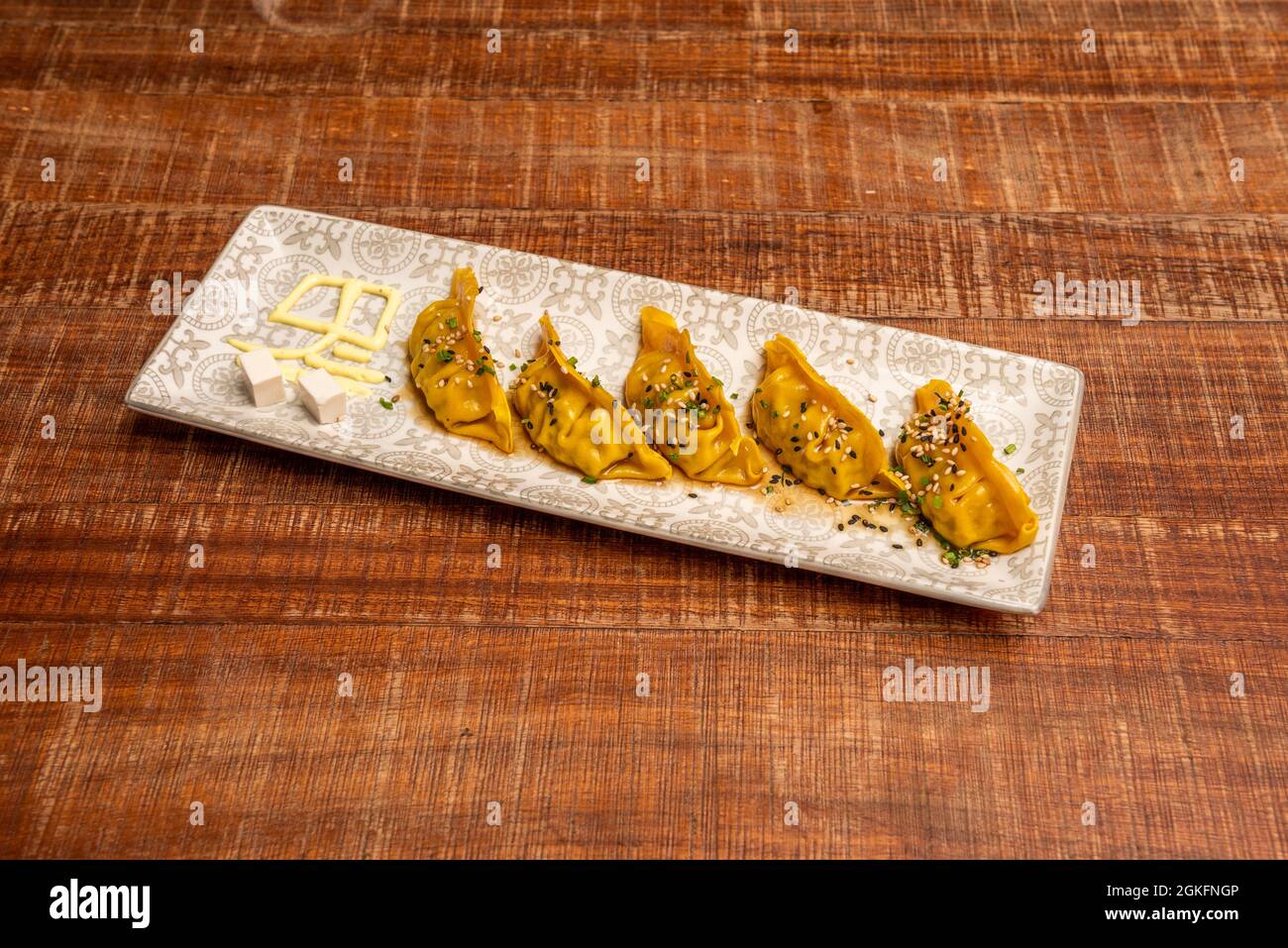 Gedünstete japanische Knödel mit gelbem, gelbem, gelbem, mit Schnittlauch und Mohnsamen und einer grauen Schale mit Sesambohrung Stockfoto