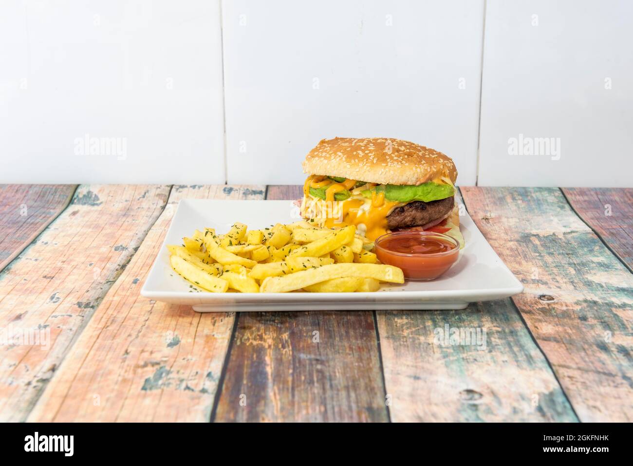 Rinderburger mit geschmolzenem Cheddar-Käse, Salat, Beilage-Pommes und Ketchup-Sauce zum Eintauchen Stockfoto