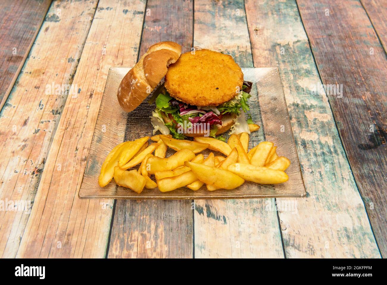 Hähnchenburger im Teig, mit viel Salat, rustikalem Brot und einer Seite Pommes Frites Stockfoto