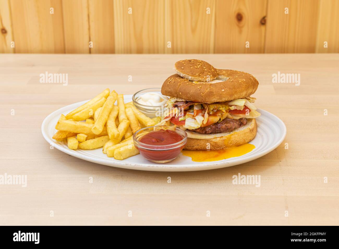 Spezieller Hamburger mit frittiertem Eigelb auf Salat und Fleisch, zwei Kugeln mit Mayonnaise und Ketchup-Sauce und einer Seite Pommes frites Stockfoto
