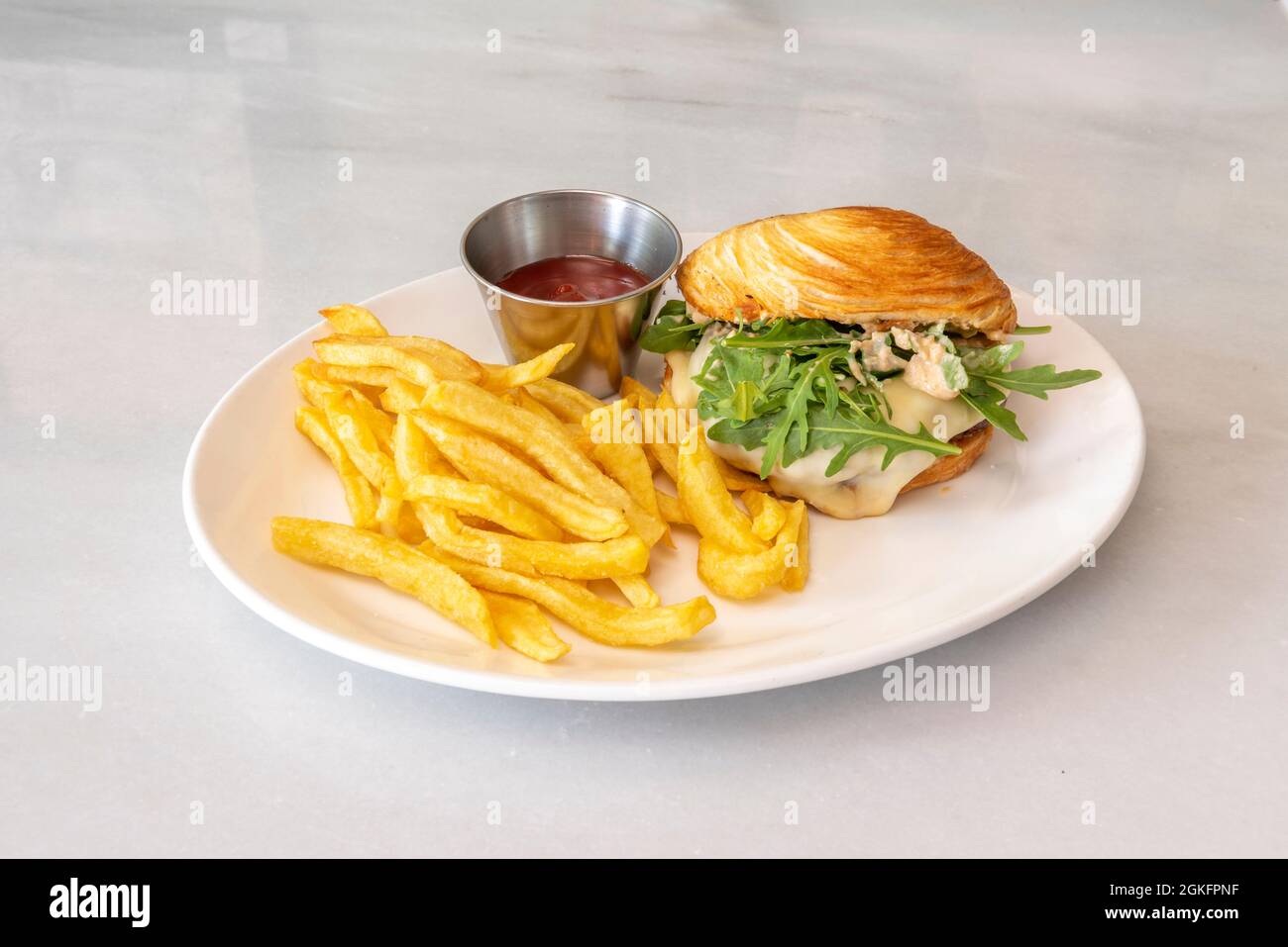Entenfleisch-Burger im französischen Stil mit Croissant-Brot, Pommes Frites und Ketchup Stockfoto