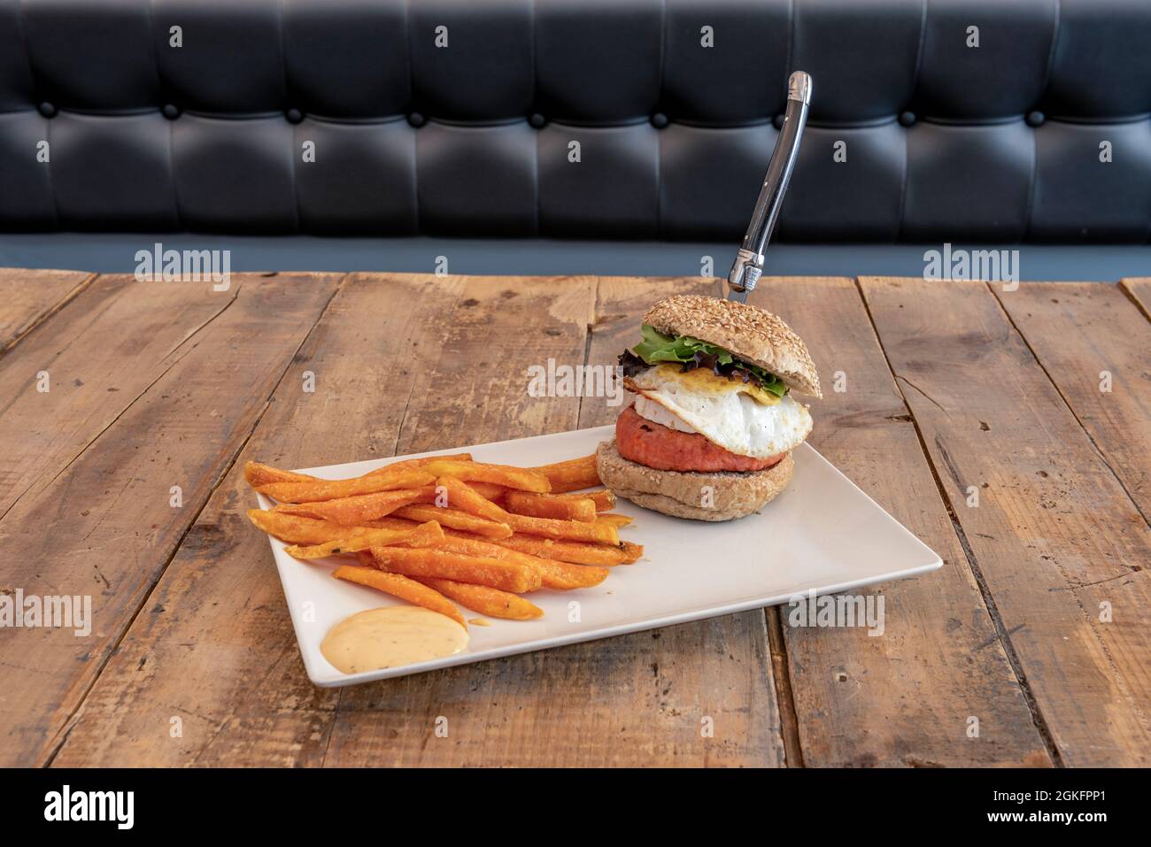 Hamburger mit Ei und Ziegenkäse, begleitet von gebratener Süßkartoffel Stockfoto
