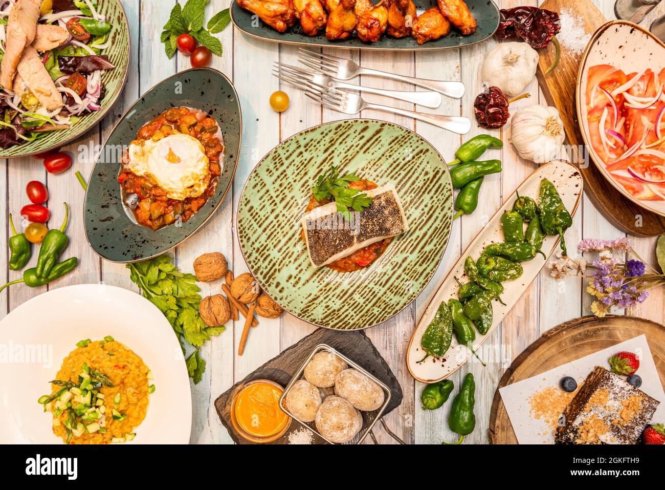 Set von typisch spanischen Gerichten Draufsicht mit Nüssen, Knoblauch, Koriander, Kirschtomaten, zerknittert Kartoffeln, Bauch und Gabeln Stockfoto