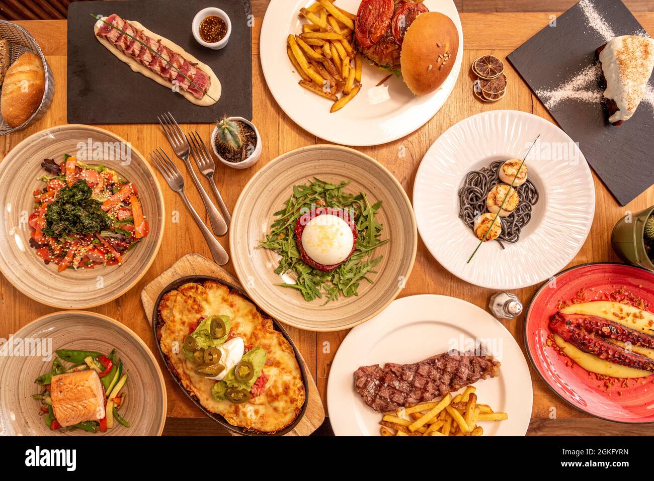 Auswahl an italienischen und mexikanischen Gerichten, Hamburger auf Holztisch Stockfoto