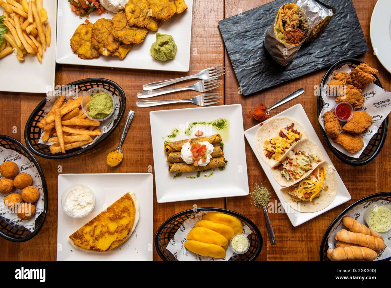 Bild von oben mit Tex-Mex-Gerichten und venezolanischen Gerichten. Tacos, Tequenos, arepas, guacamoles, cachapa, Kroketten, Pataconen, goldene Tacos Stockfoto