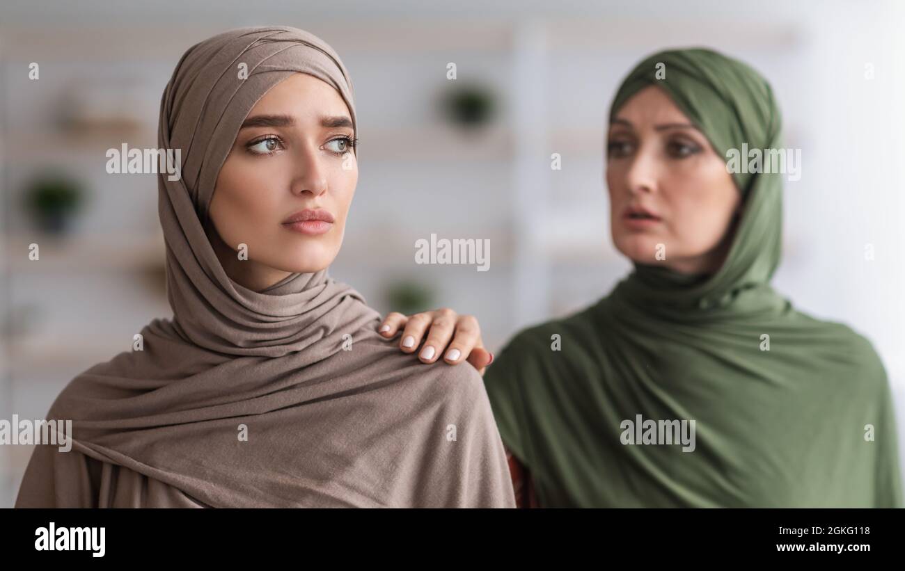 Ältere Muslimische Mutter Berührt Die Schulter Einer Unglücklichen Erwachsenen Tochter In Der Halle Stockfoto