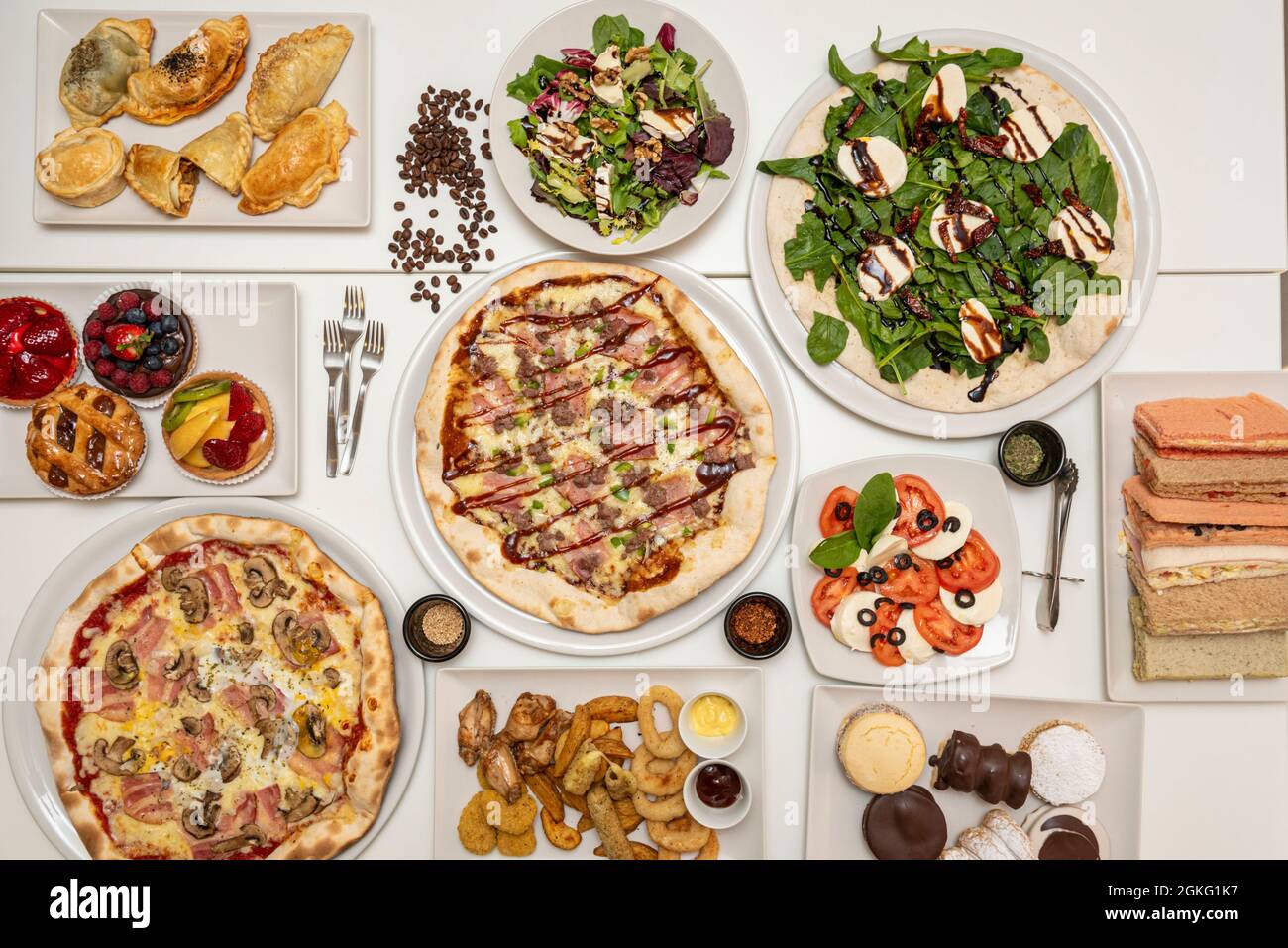 Zusammensetzung mit Pizzaplatten, Törtchen, Salaten, Sandwiches, Empanadas, Vorspeisen und argentinischer Kuchen Stockfoto