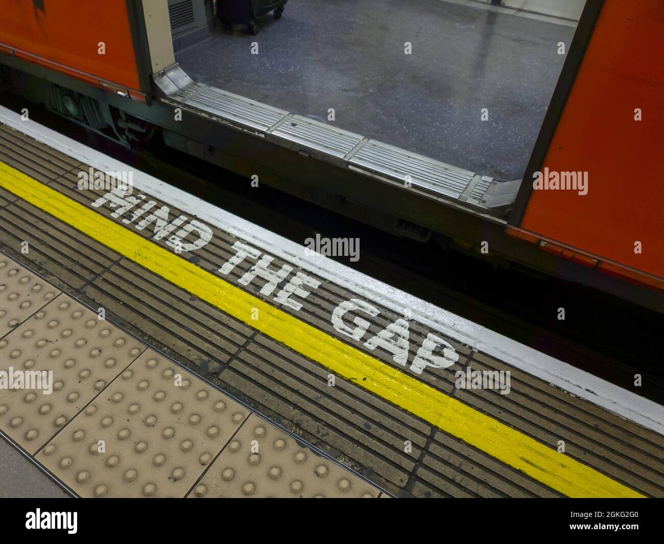 Markierungen und Worte auf einer Plattform warnen die Passagiere vor der Lücke zwischen der Plattform und dem Zug. Stockfoto