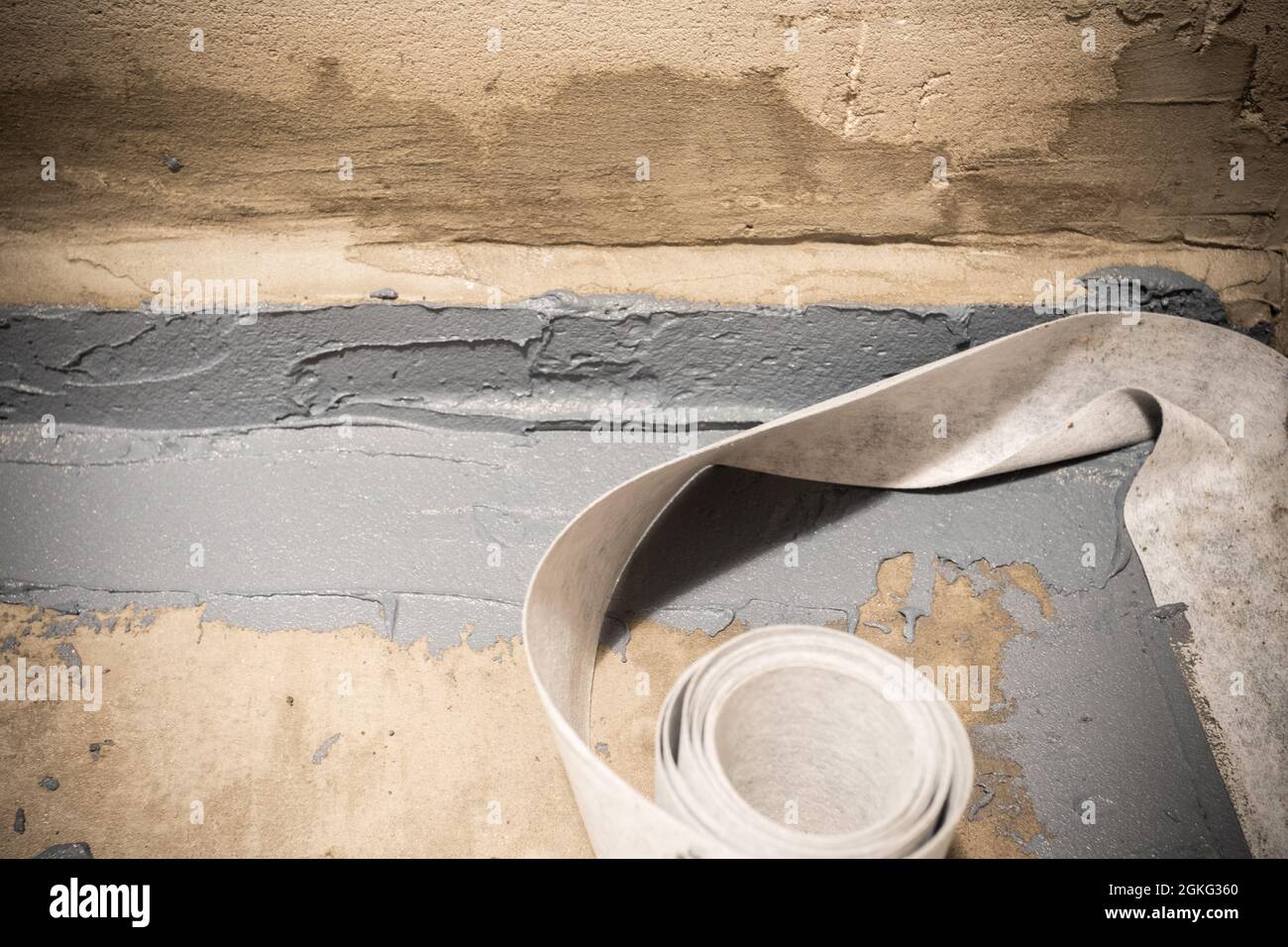 Anbringen eines Abdichtbandes an der Fuge zwischen Wand und Boden. Interne Bauarbeiten Anbringen eines Abdichtbandes an der Fuge zwischen Wand und Boden. Interne Bauarbeiten