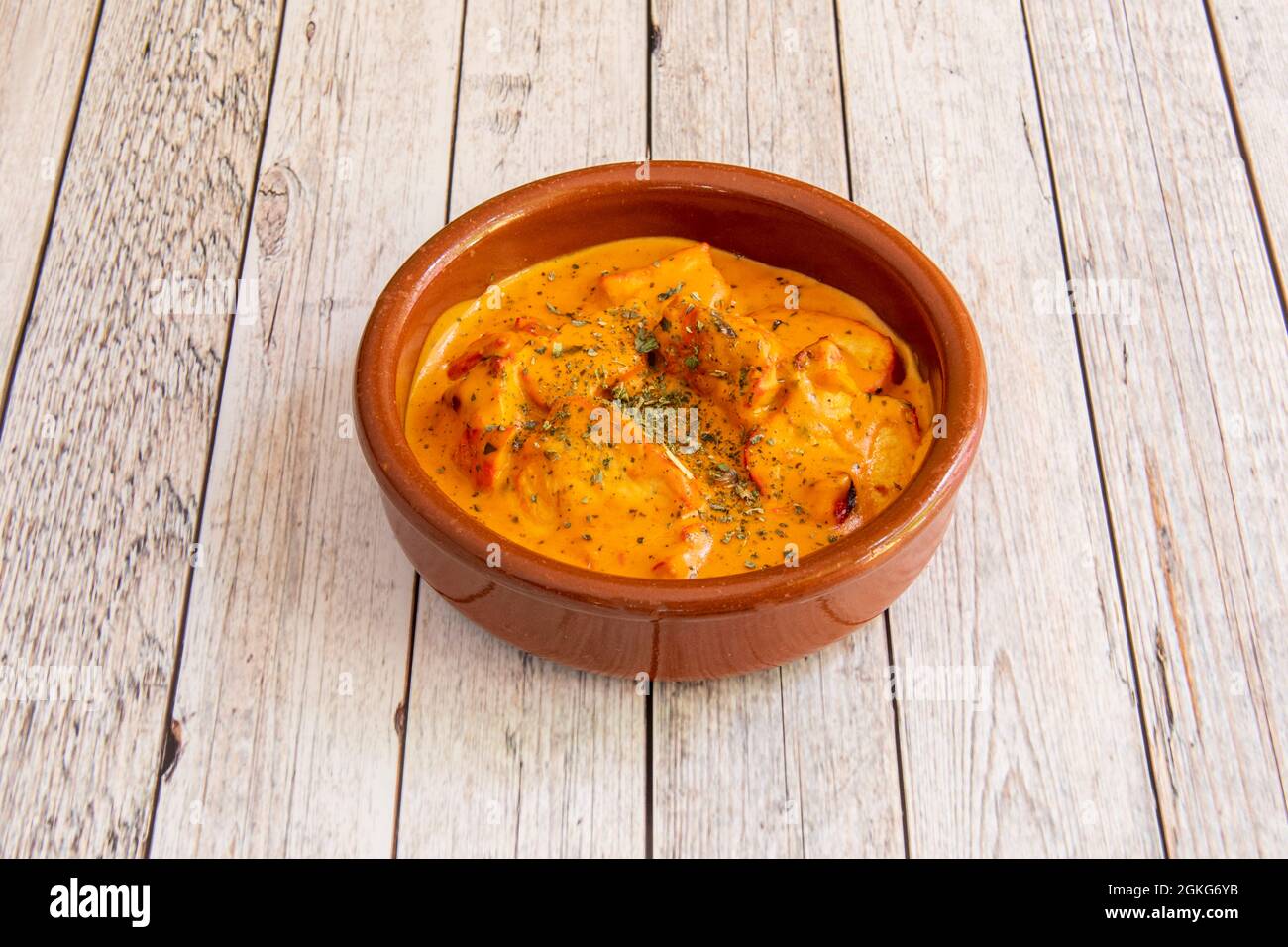 Tontopf mit einer Portion mildem, korma, Huhn auf einem hellen Holztisch Stockfoto