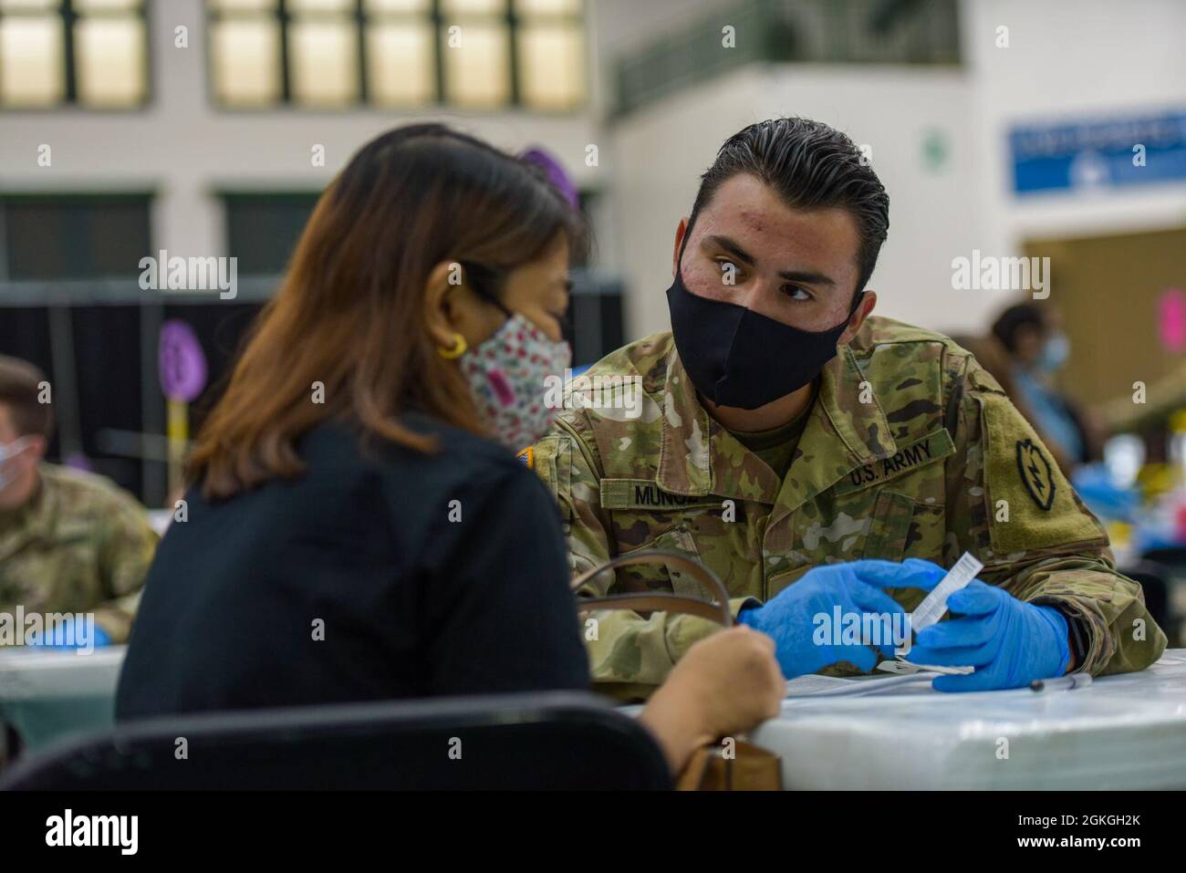 MANGILAO, Guam (16. April 2021) – PFC. Enricke Munoz, ein Kampfmediziner, der der 25. Infanterie-Abteilung zugewiesen wurde, erklärt die Impfkarte, bevor er einen COVID-19-Impfstoff zur Unterstützung des COVID-19-Impfteams des Gesundheitsministeriums von Guam (DPHSS) in einer Impfklinik im Field House der Universität von Guam Calvo verabreicht. Das US-amerikanische Indo-Pacific Command über die US Army Pacific ist weiterhin bestrebt, die Federal Emergency Management Agency im Rahmen der Reaktion der gesamten Regierung auf COVID-19 weiterhin flexibel zu unterstützen. Stockfoto