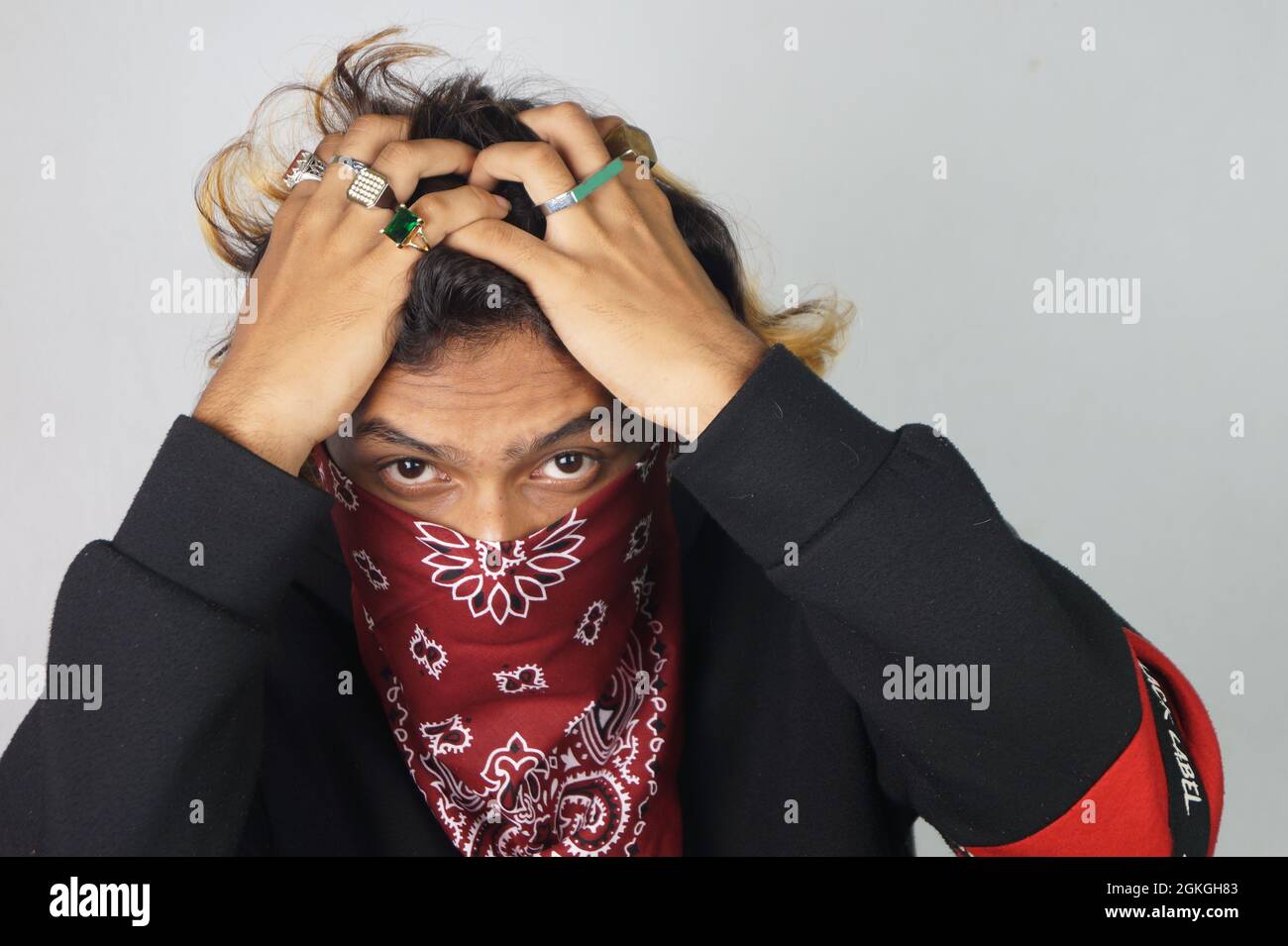 Ein junger Mann mit einem Bandana, der sein Gesicht bedeckt und Ringe an  seinen Fingern hat Stockfotografie - Alamy