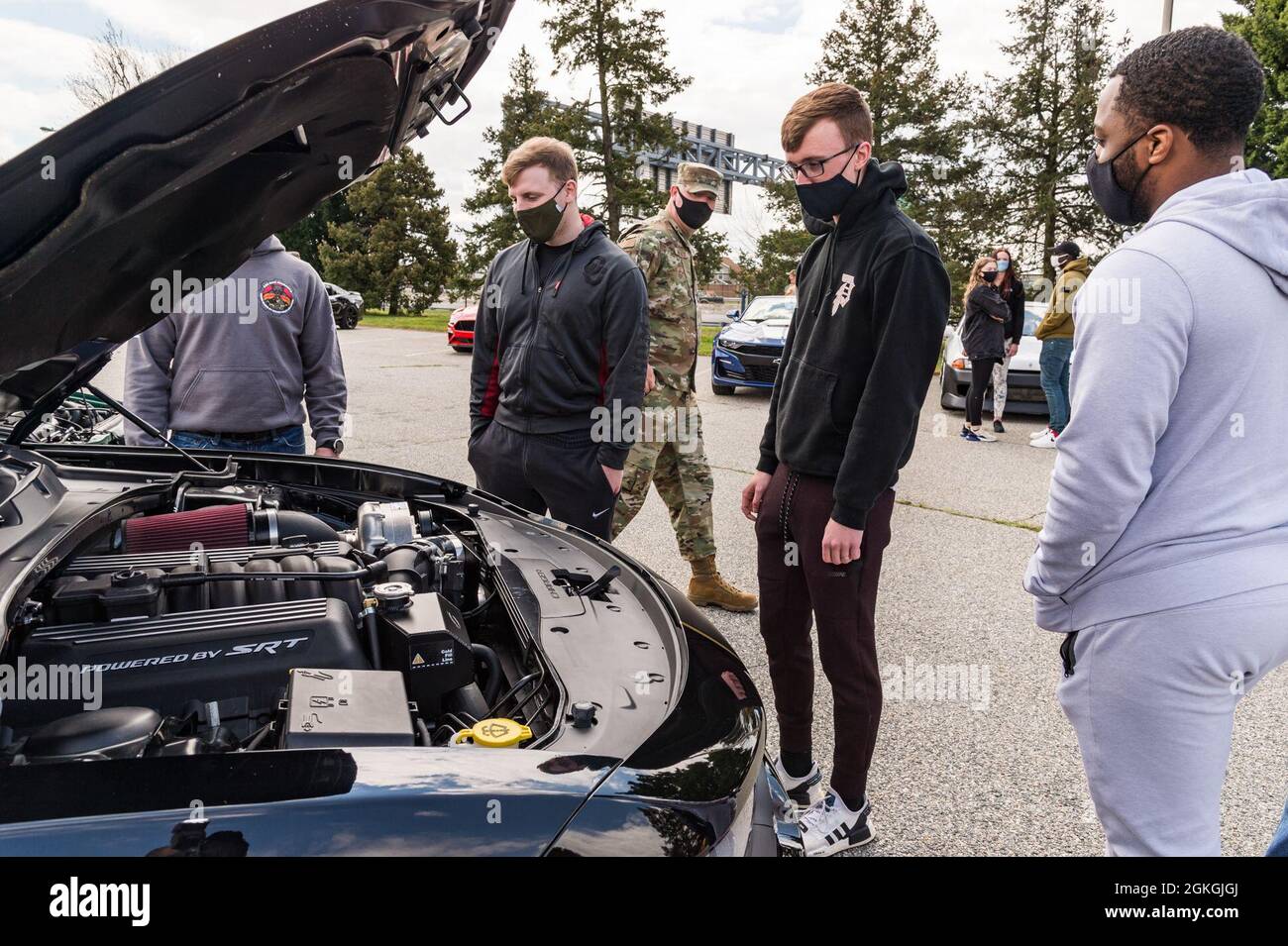 Die Mitglieder des Teams Dover beobachten einen Automotor während der Auto- und Fahrradmesse am Wingman Day auf dem Luftwaffenstützpunkt Dover, Delaware, 16. April 2021. 36 Autos und vier Motorräder kamen in die Show. Stockfoto