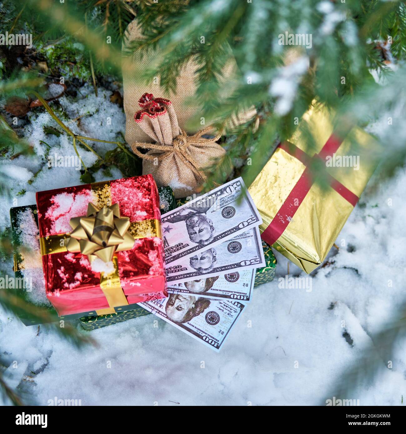 Geschenke in roten Schachteln und Geld in US-Dollar liegen im neuen Jahr unter dem Weihnachtsbaum Stockfoto