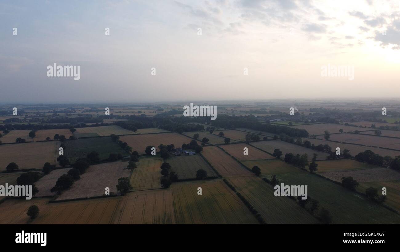 Ein Blick aus der Luft über die flachen Felder und Weiden in den Dunst vor uns, mit Sonnenuntergang im Westen. Stockfoto
