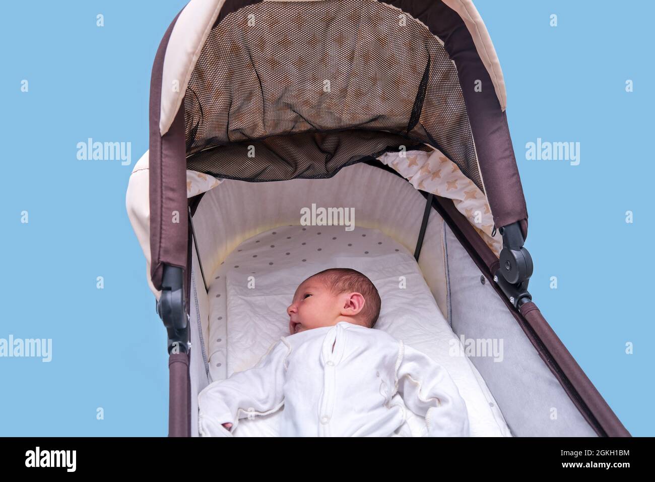 Kleiner Junge in einem Kinderwagen auf blauem Hintergrund. Ein Kind in  weißen Kleidern in nur Windeln liegt in einem Kinderwagen, Studioaufnahme  Stockfotografie - Alamy