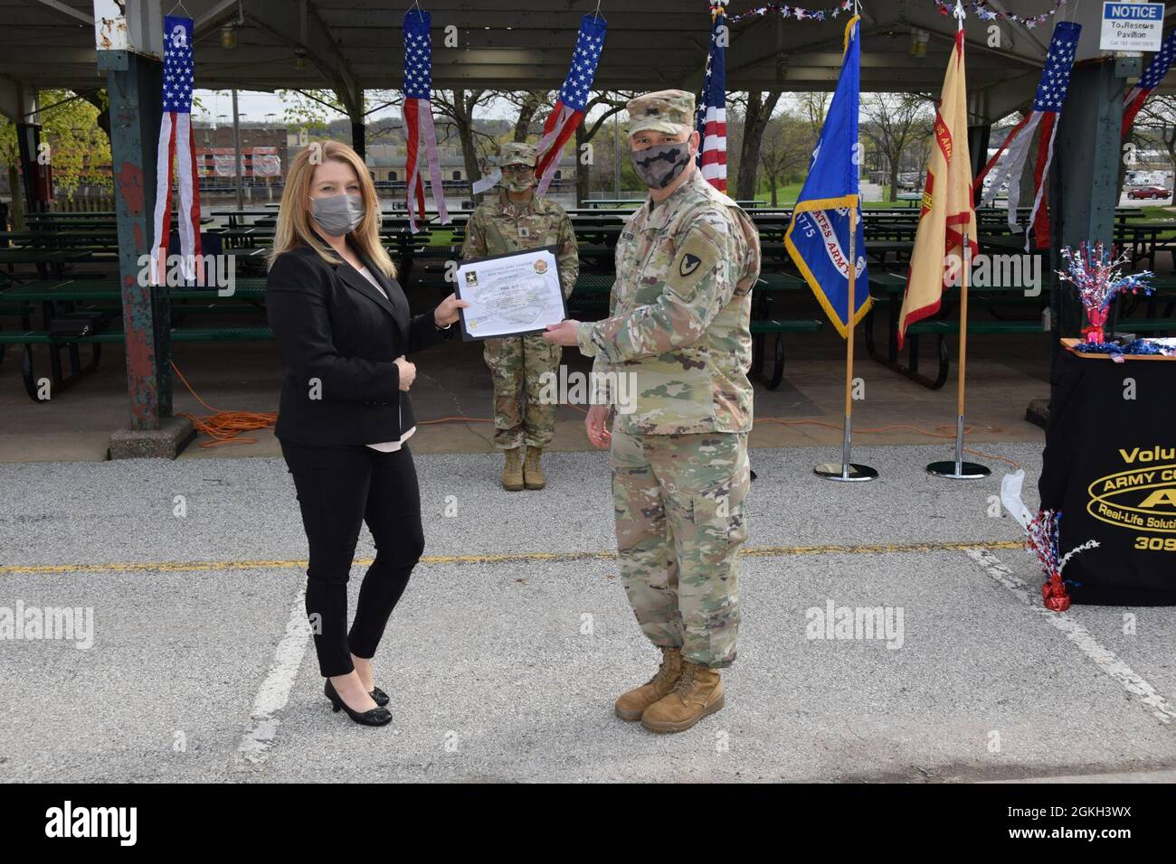 Col. Todd Allison überreicht Tyne Jett während der Ehrenamtszeremonie, die am 20. April im Memorial Park auf Rock Island Arsenal stattfand, eine Dankungsurkunde für ihre Arbeit mit Toys for Tots. Stockfoto