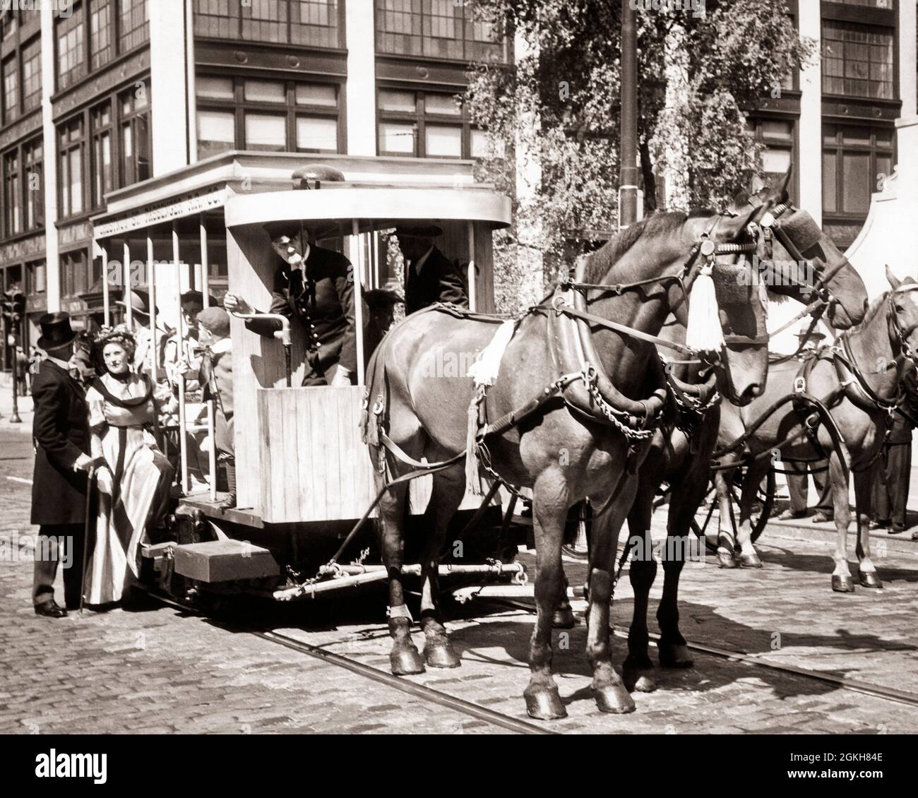 DER AUS DEN 1950ER JAHREN STAMMENDE PFERDEWAGEN AUS DER JAHRHUNDERTWENDE AUF DER BACKSTEINSTRASSE, IN DEM PASSAGIERE IN KOSTÜMEN AUS DER 1890ER-JAHRE AUFSTEIGEN BRETT - C824 HAR001 HARS ROMANTIK GEMEINSCHAFT STEIN URBAN IMMER ALTE ZEIT DIRIGENT NOSTALGIE ALTE MODE 1 JUVENILE BLOCK PFERDE TEAMWORK TURN KOSTÜME LIFESTYLE SCHAUSPIELER GESCHICHTE BACKSTEIN FEIER FRAUEN PASSAGIERE KOPIEREN RAUM IN VOLLER LÄNGE DAMEN PERSONEN MÄNNER UNTERHALTUNG TRANSPORT S & W FILME SÄUGETIERE FILME ABENTEUER KINOS DER JAHRHUNDERTWENDE AUFREGUNG FORTSCHRITT INNOVATION GEZEICHNET TROLLEY SCHAUSPIELER STILVOLLE FILM-FILME WERBUNG NOCH JUVENILES SÄUGETIER Stockfoto