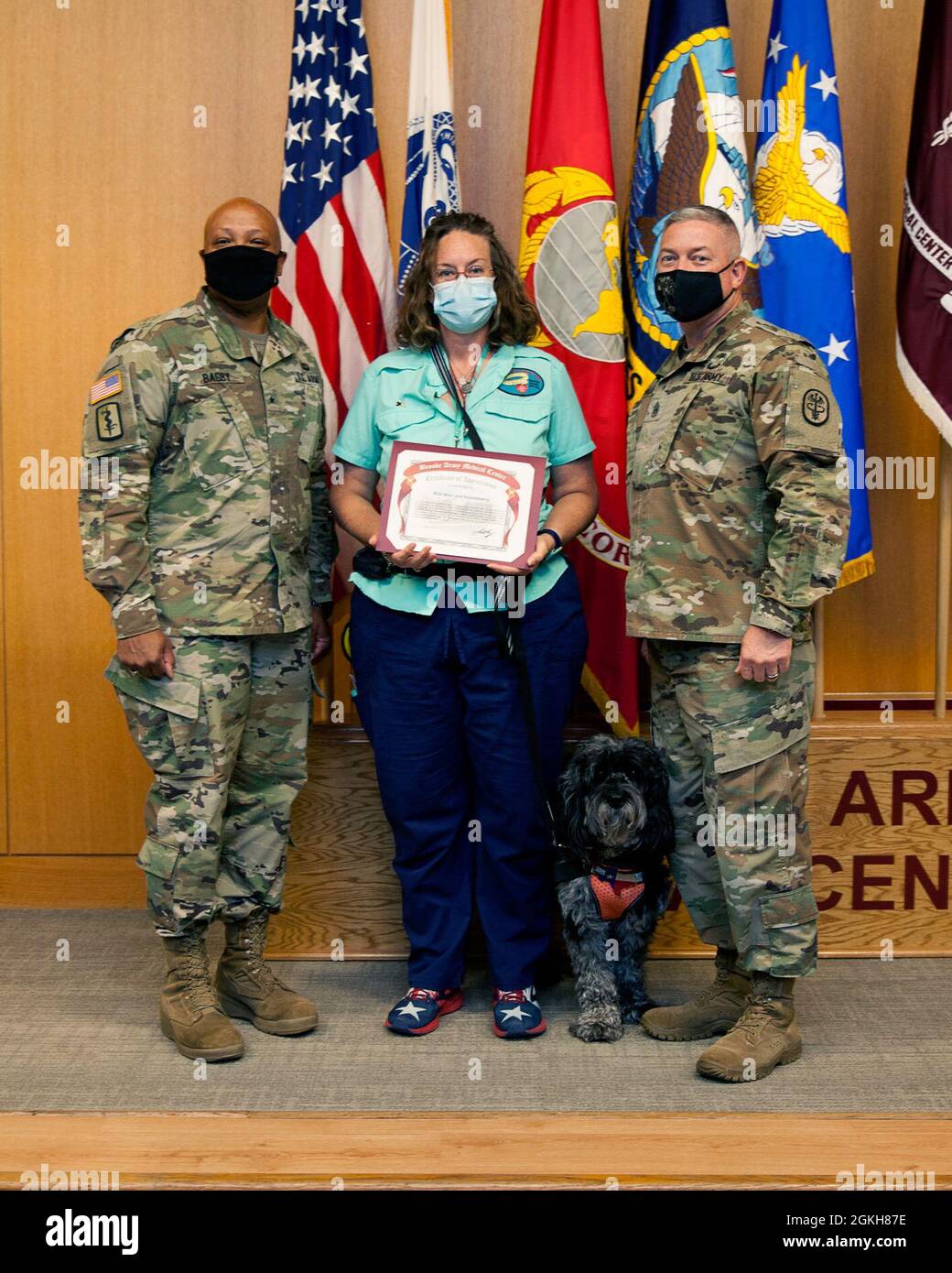 Das Medizinische Zentrum Der Armee Von Brooke Kommandiert General Brig. General Shan Bagby und Command Sgt. Maj. Thurman Reynolds stellt Kris Blair und den Therapiehund Huckleberry vor und sind eine Dankesurkunde für ihren ehrenamtlichen Einsatz während einer Ehrenamtszeremonie im BAMC, Fort Sam Houston, Texas, am 21. April 2021. Blair und Huckleberry nahmen auch an der ersten Woche der Ausfallsicherheit durch BAMC vom 19. Bis 23. April 2021 Teil. Stockfoto