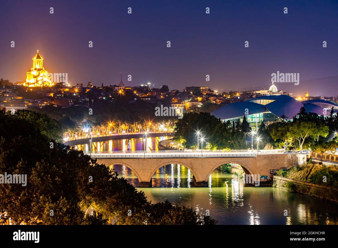 Malerische Aussicht auf den Fluss Mtkvari und die Kathedrale der Heiligen Dreifaltigkeit in der Nacht beleuchtet in Tiflis Georgien Stockfoto