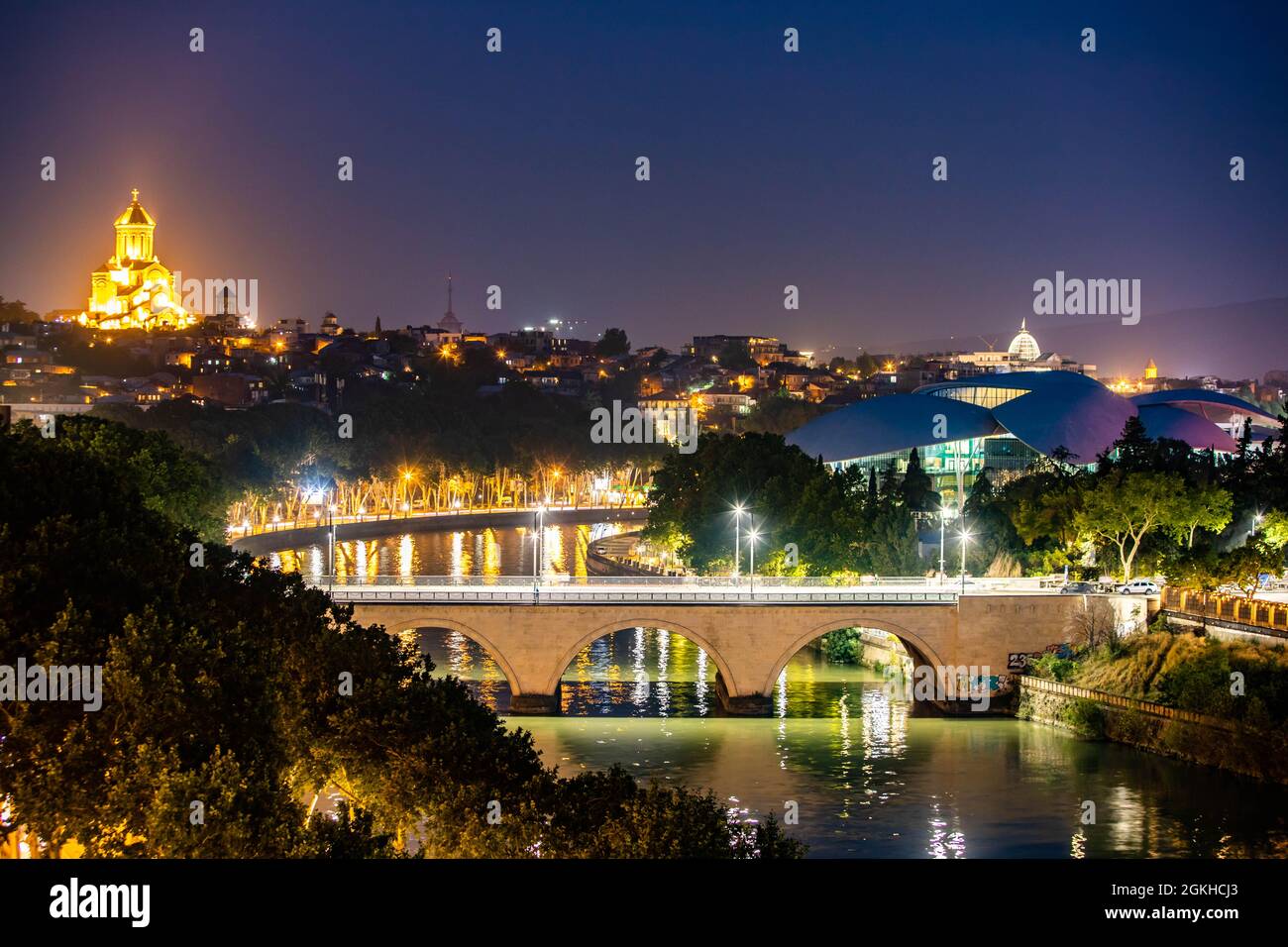 Malerische Aussicht auf den Fluss Mtkvari und die Kathedrale der Heiligen Dreifaltigkeit in der Nacht beleuchtet in Tiflis Georgien Stockfoto