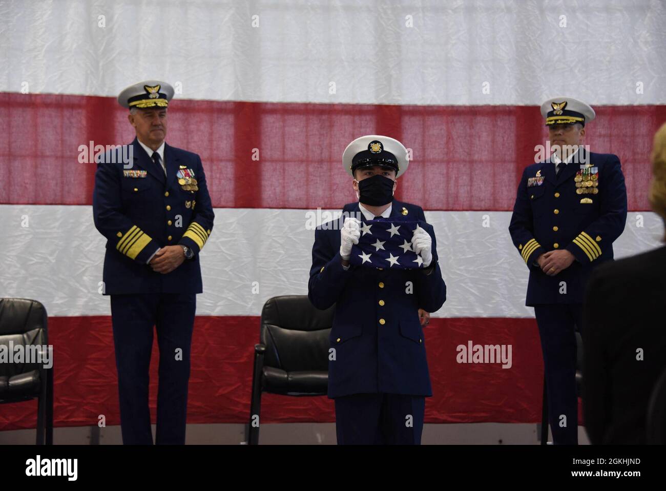 Douglas Munro, Mitglied der Küstenwache (WHEC 724), stellt während der Stilllegungszeremonie der Schneider in Kodiak, Alaska, am 24. April 2021 einen Wimpel vor. Während des letzten Dienstjahres des Cutter absolvierte der Cutter 159 Tage außerhalb des Heimathafens Patrouillen über 23,000 Seemeilen in der Beringsee, im Golf von Alaska und im Pazifischen Ozean, um Gesetze, Verträge und Vorschriften durchzusetzen, die für die Erkennung und Abschreckung von illegaler, unregulierter und nicht gemeldeter (IUU) Fischerei entscheidend sind. Stockfoto