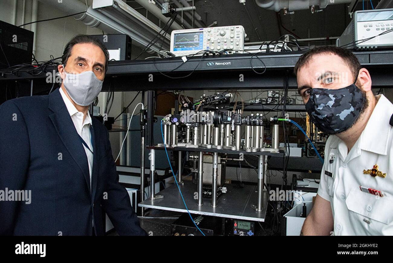 NPS-Physikprofessor Frank Narducci, links, und NPS-Student Royal Canadian Navy LT. Cmdr. Darryl Gervis, Stand by a Dual Atom Interferometer Accelerometer/Gyroscope, von dem Gervis einen Teil seiner an der Fakultät geleiteten Forschung nutzt, um die Quantenerkundung voranzutreiben. Stockfoto