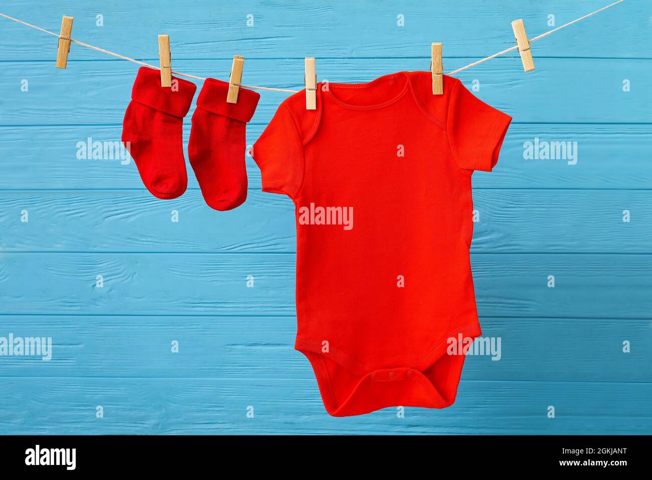 Babykleidung hängt am Seil vor farbigem Holzhintergrund Stockfotografie -  Alamy