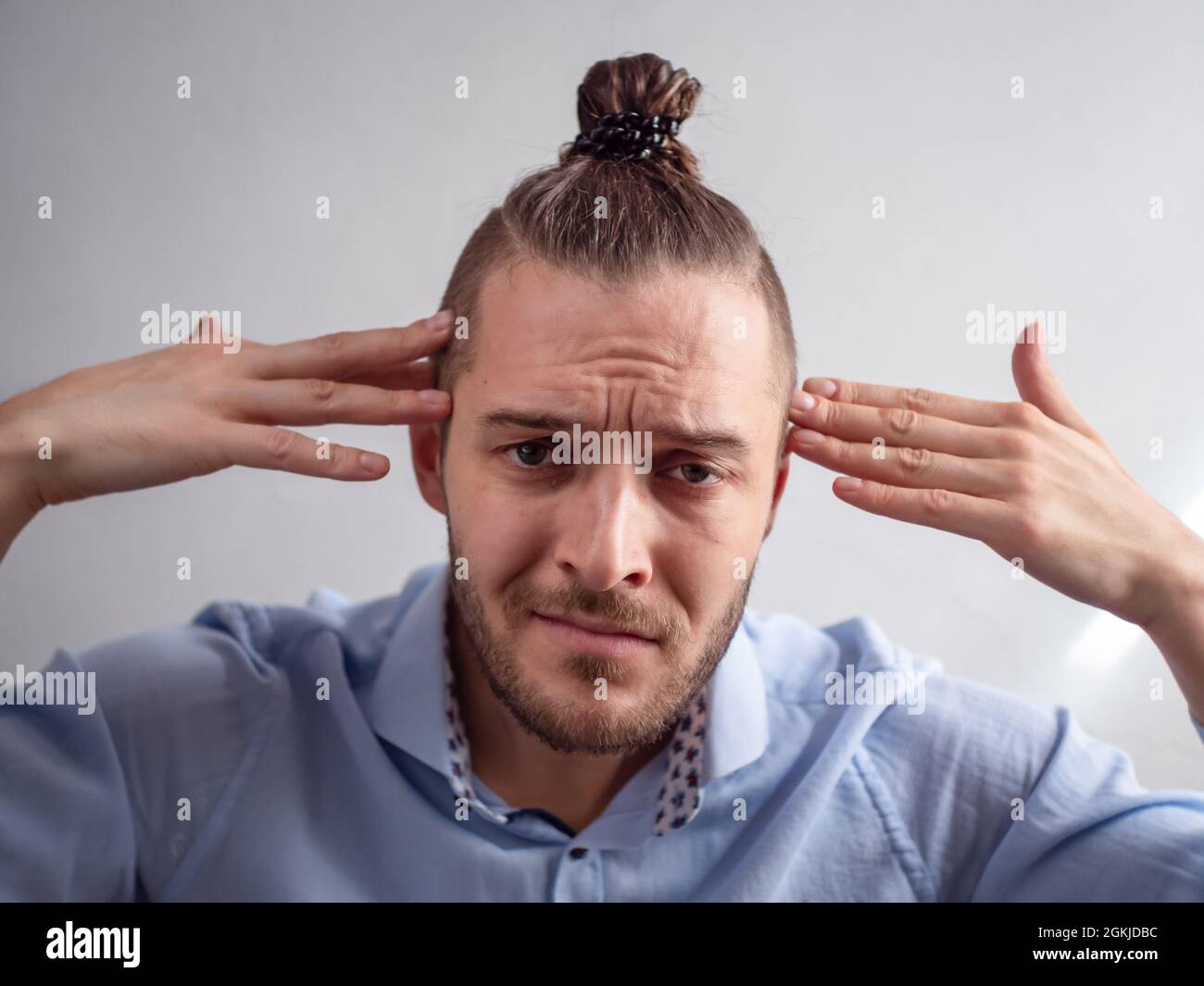 Weißer junger Mann sieht verwirrt aus mit Händen auf seinem Kopf Stockfoto